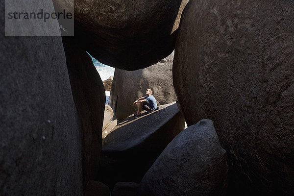 Felsbrocken  Außenaufnahme  Mann  sitzend  Sonnenlicht  Höhle  Regenwald  Britische Jungferninseln
