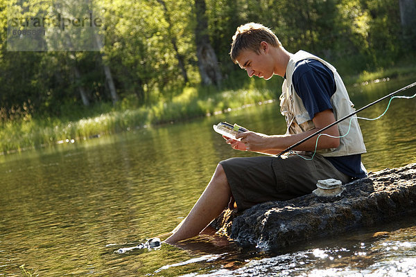 nahe  Felsbrocken  Jugendlicher  sitzend  Junge - Person  Fluss  auswählen  angeln  Schwan