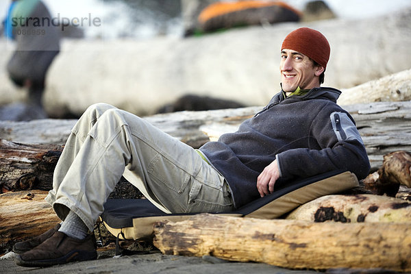 Mann Entspannung liegend liegen liegt liegendes liegender liegende daliegen Strand Treibholz