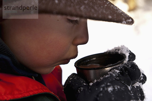 Außenaufnahme  Tasse  Junge - Person  blasen  bläst  blasend  Wärme  Schokolade  jung  Schnee