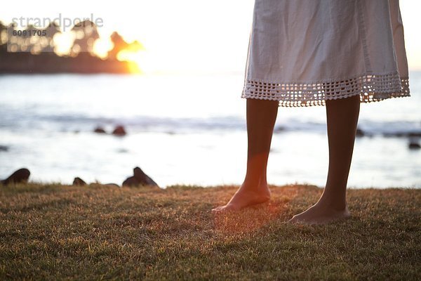 Frau  gehen  Sonnenuntergang  über  Meer  barfüßig  Gras  Kleid