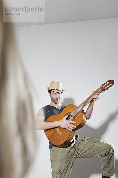 Mann zupft Gitarre  lächelnd