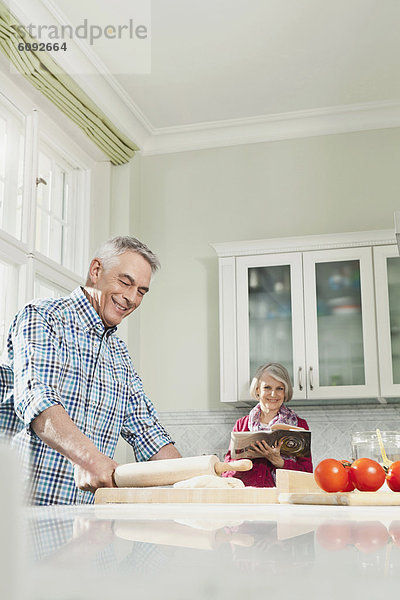Man preparing food  woman with book in background