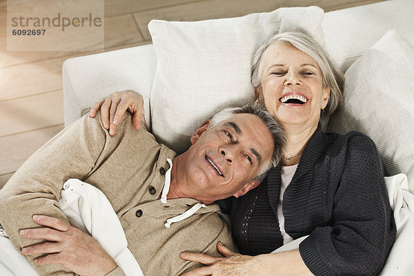 Deutschland  Berlin  Seniorenpaar auf Couch liegend  lächelnd