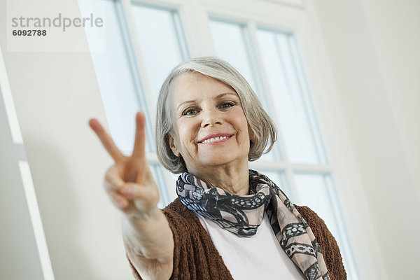 Seniorin mit Friedenszeichen  lächelnd  Portrait