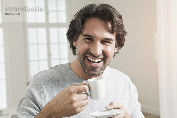 Erwachsener Mann mit Kaffeetasse  lächelnd  Portrait