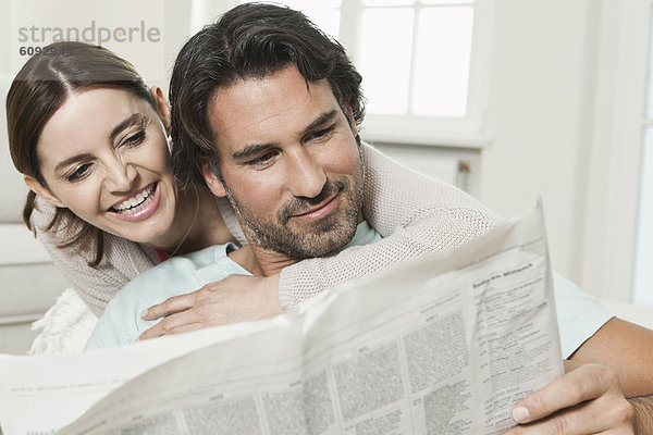 Deutschland  Berlin  reifes Paar beim Zeitung lesen  lächelnd