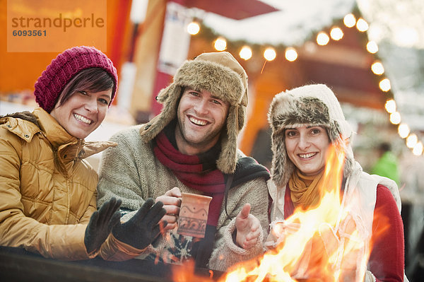 Österreich  Salzburg  Mann und Frau beim Feuer auf dem Weihnachtsmarkt  lächelnd