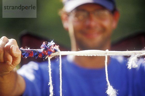 Climber holds up half cut  fraying climbing rope.