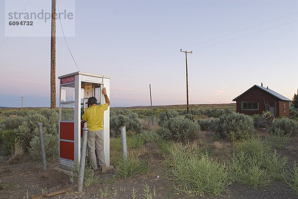 A man phones from a isolated phone booth.