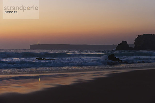 Portugal  Algarve  Sagres  Blick auf den Strand mit brechenden Wellen bei Sonnenuntergang