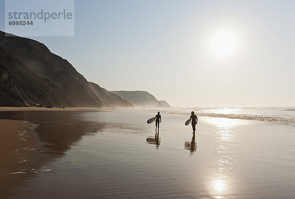 Portugal  Paar Wandern mit Surfbrett am Strand