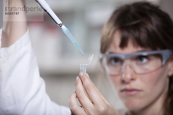 Deutschland  Bayern  München  Wissenschaftler mit Pipette und Reagenzglas im Labor