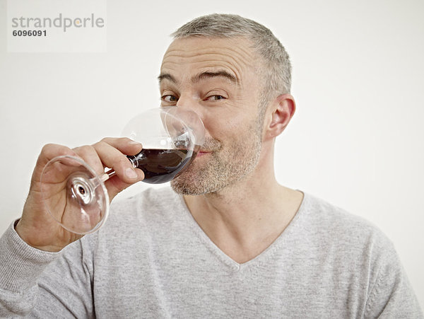 Reifer Mann trinkt Wein in der Küche  Porträt