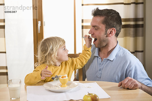 Tochter füttert gekochtes Ei an Vater