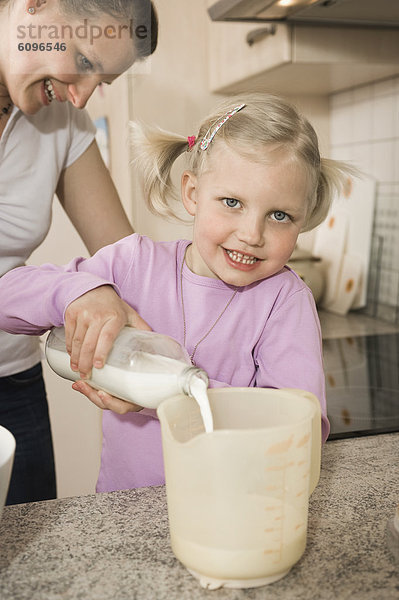 Mother and daughter pouring milk into measuring cup