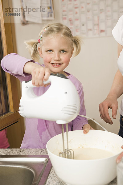 Mother and daughter mixing batter with electric whisk