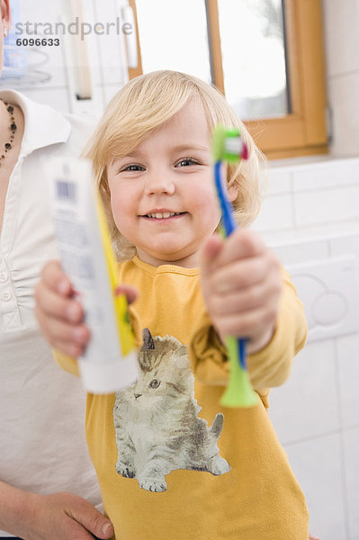 Girl showing toothbrush and toothpaste  smiling