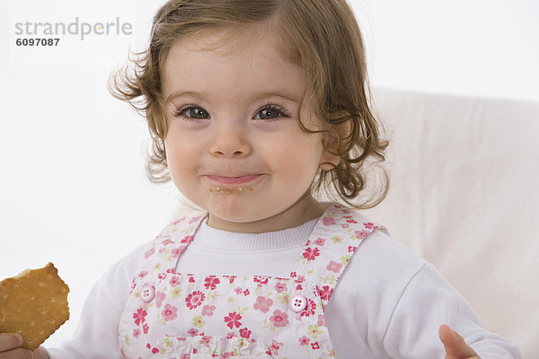 Baby girl eating cookie  smiling  close up