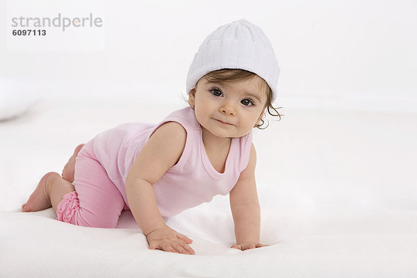 Kleines Mädchen auf Babydecke krabbelnd  lächelnd