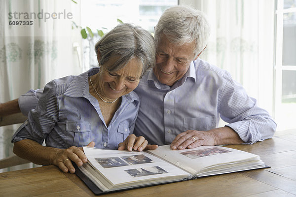 Germany  Bavaria  Senior couple with photo album  smiling