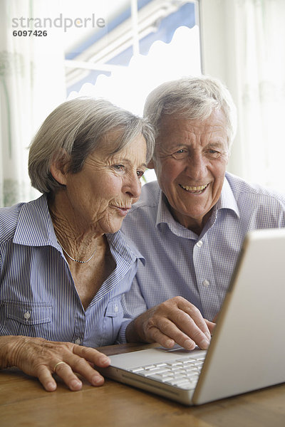 Deutschland  Bayern  Seniorenpaar mit Laptop zu Hause
