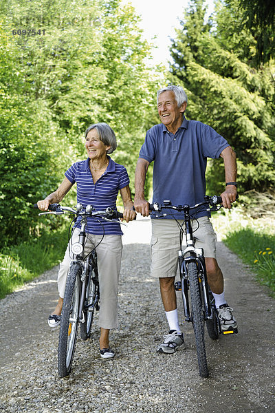 Germany  Bavaria  Senior couple with bicycle  smiling