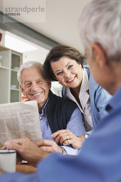Senior man reading newspaper  man and woman smiling