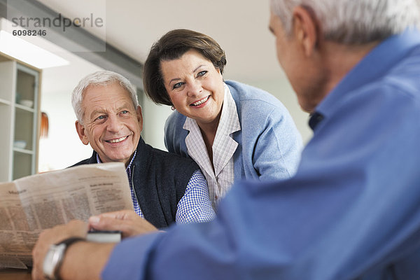 Senior Mann liest Zeitung  Mann und Frau lächeln