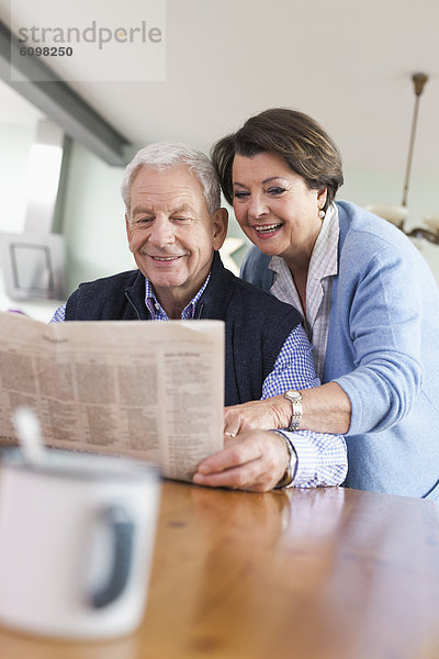 Senior man and woman reading newspaper  smiling