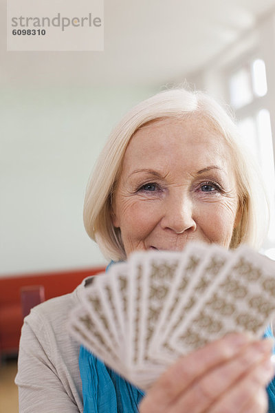 Senior woman playing cards  smiling  portrait