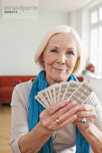 Seniorin beim Kartenspielen  lächelnd  Portrait