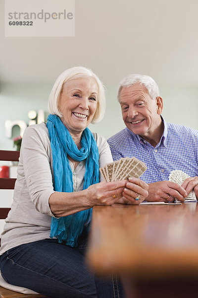 Senior man and woman playing card game  smiling