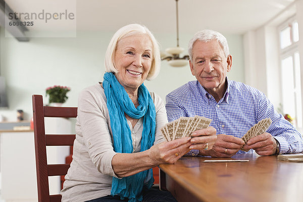 Senior Mann und Frau beim Kartenspielen  lächelnd  Porträt