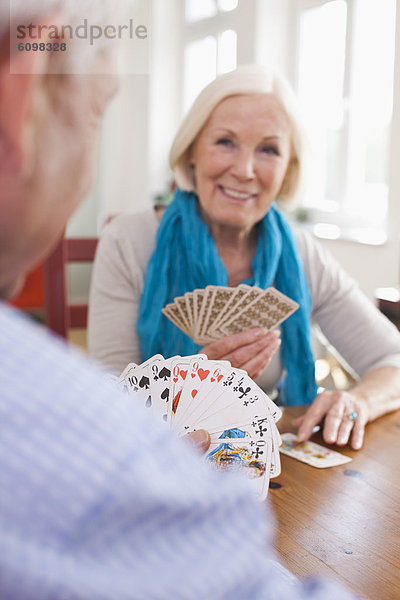 Senior man and woman playing cards  smiling