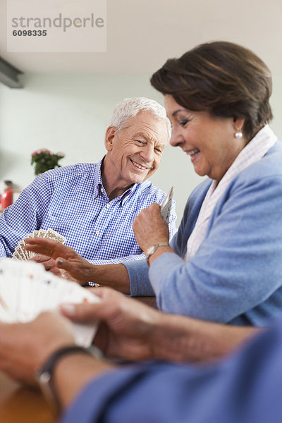 Senior men and woman playing cards  smiling