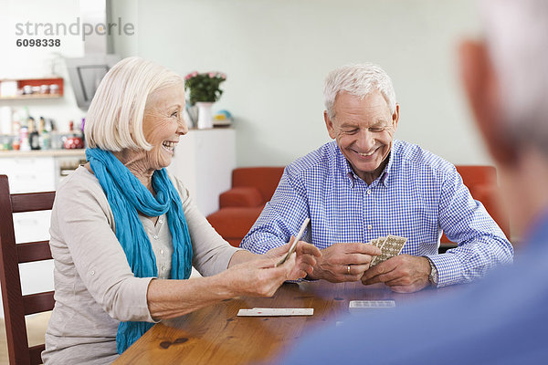 Senior men and woman playing cards  smiling