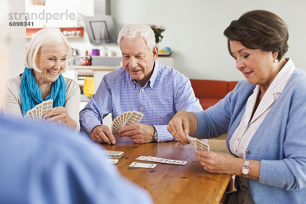 Ältere Männer und Frauen beim Kartenspielen  lächelnd