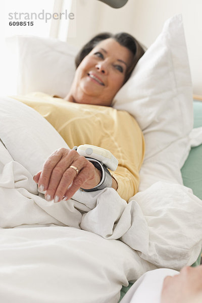 Seniorin auf dem Krankenbett liegend  lächelnd