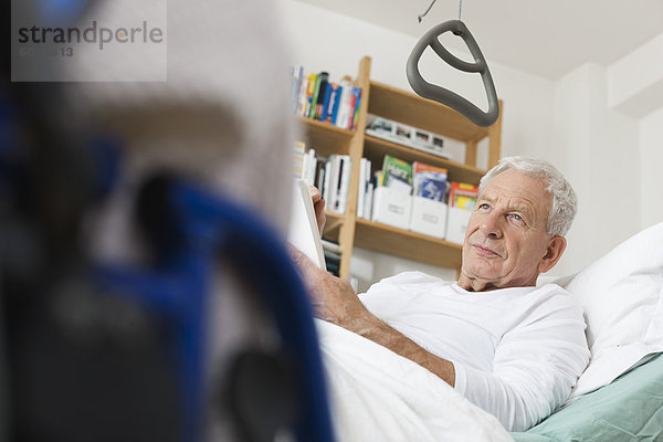 Älterer Mann auf medizinischem Bett liegend und zeichnend