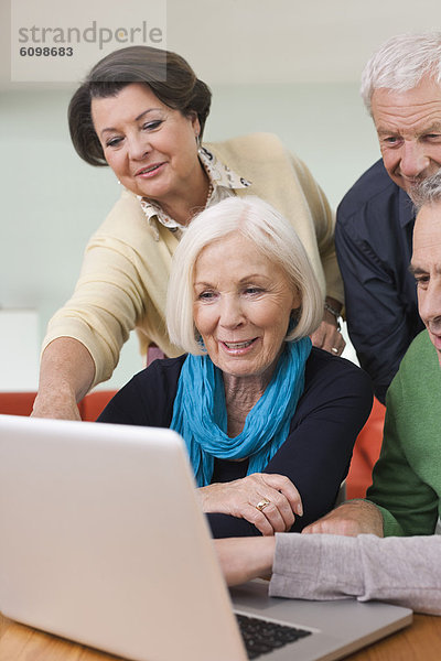 Senioren Männer und Frauen beobachten Bilder auf dem Laptop