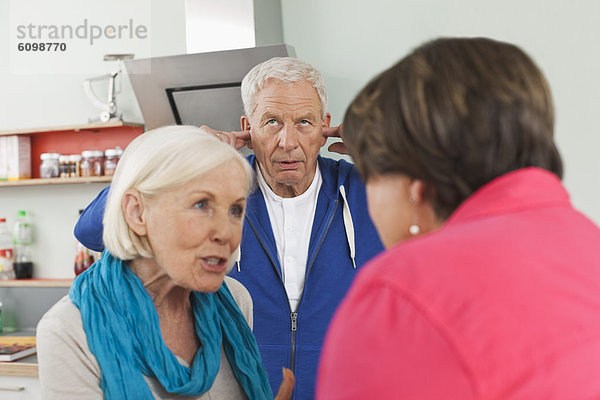 Seniorinnen diskutieren  Mann mit Ohren im Hintergrund