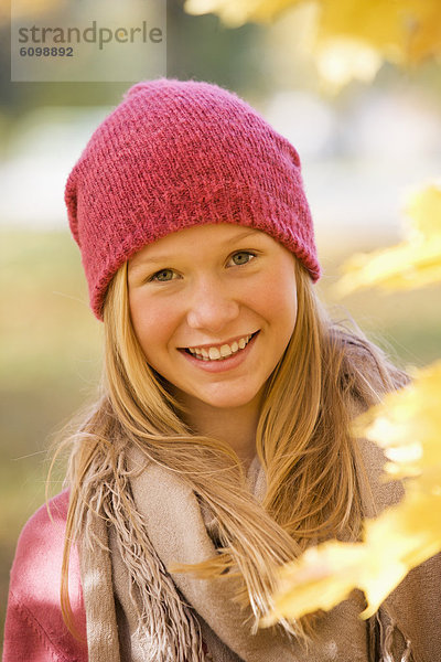 Österreich  Nahaufnahme eines jungen Mädchens mit Ahornblatt  lächelnd