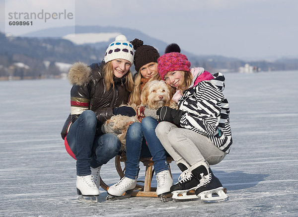 Österreich  Teenagermädchen sitzend auf Schlitten mit Hund  Portrait