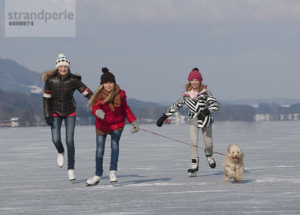 Österreich  Jugendliche Mädchen beim Eislaufen mit Hund