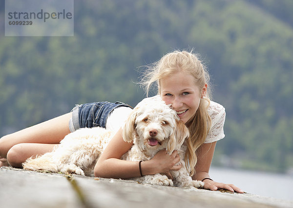 Austria  Teenage girl with dog on jetty  smiling  portrait