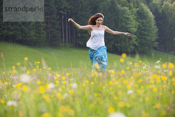 Österreich  Junge Frau beim Laufen im Blumenfeld