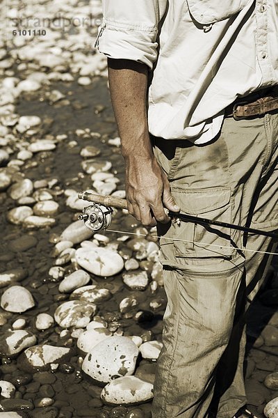 hinter  Felsbrocken  halten  weiß  Fluss  angeln  Seitenansicht  Fischer  Stange