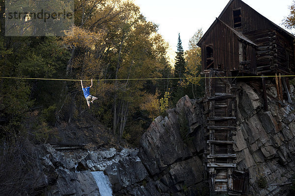 hoch oben schaukeln schaukelnd schaukelt schwingen schwingt schwingend Mann Fluss jung unterhalb Linie