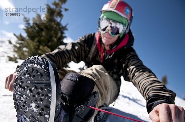 Berg  Snowboard  Snowboardfahrer  sitzend  Schutzbrille  Stiefel  Krawatte  Kleidung  Seitenansicht  Helm